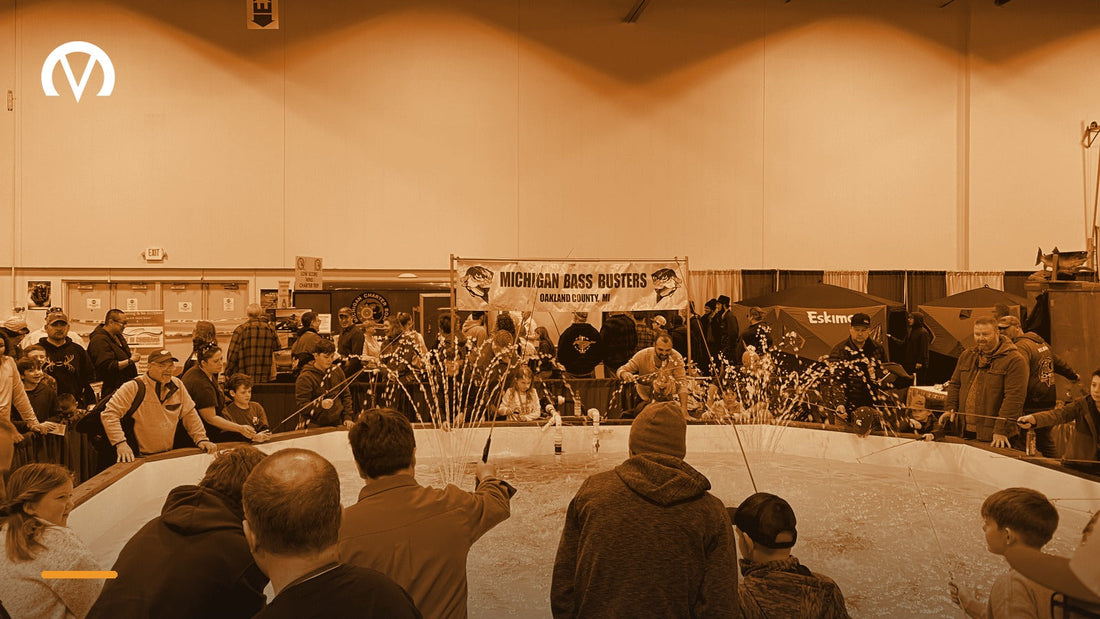 Families gathered around an indoor fishing pond demonstration at a consumer show, with vendor booths and banners behind them.