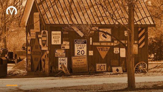 A weathered barn wall covered edge to edge with dozens of old road signs and advertising signs.