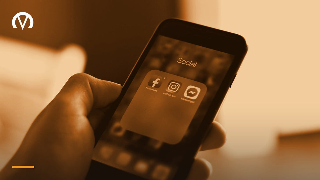 A hand holding a phone open to a folder of social media apps including Facebook, Instagram and Messenger.