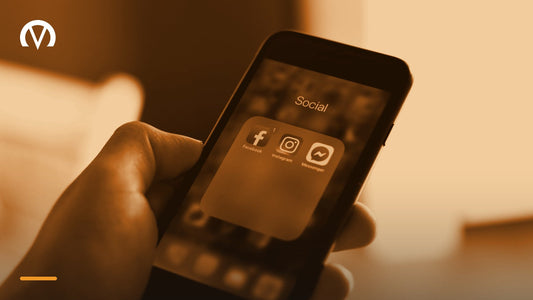 A hand holding a phone open to a folder of social media apps including Facebook, Instagram and Messenger.